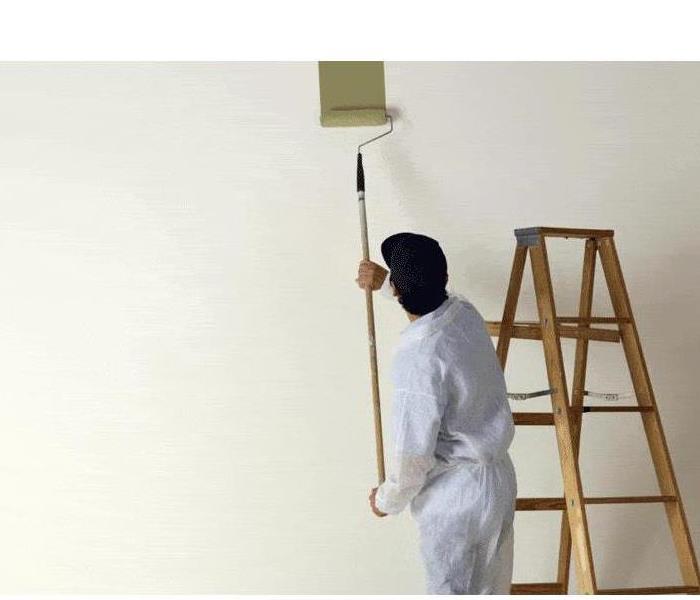 Man painting a wall with a step ladder